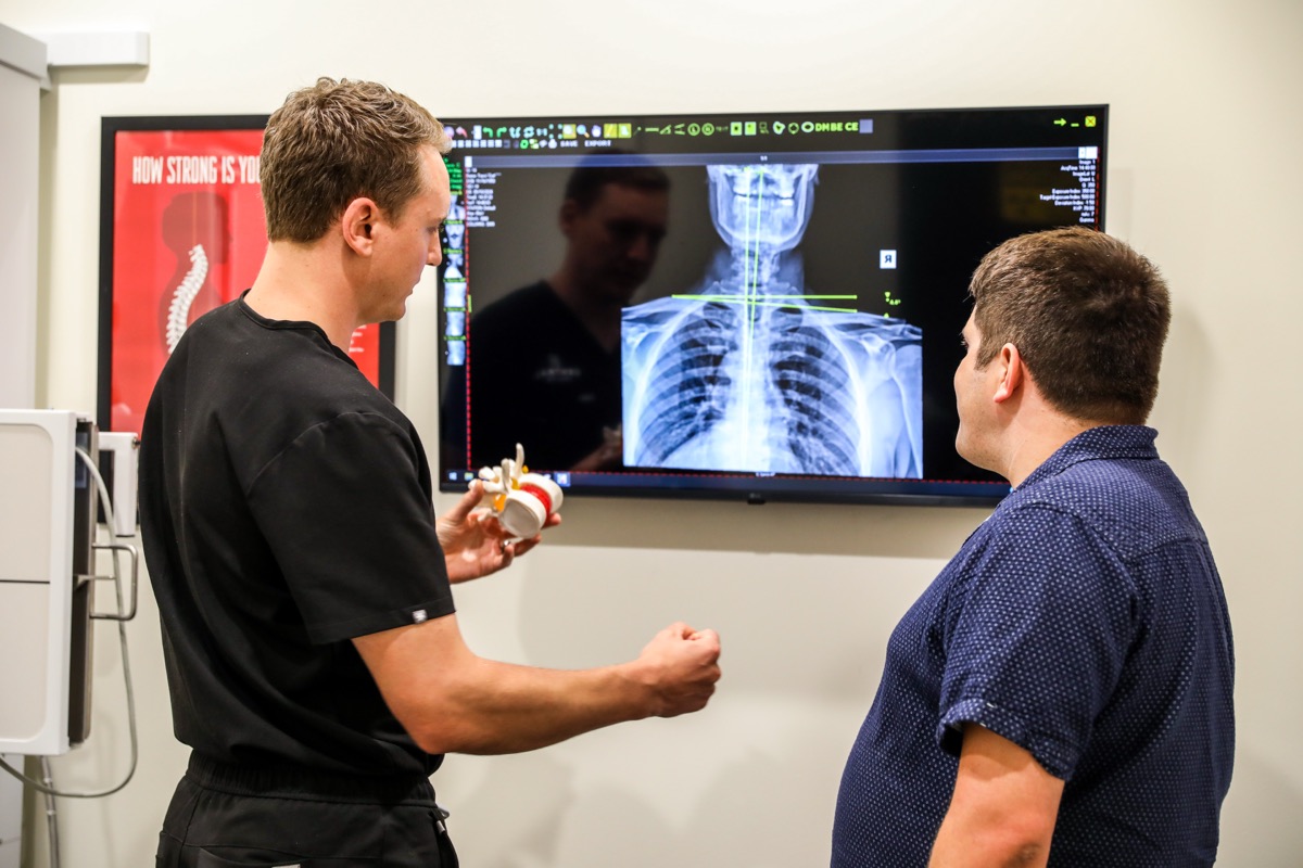 Dr. Emmerich reviewing a spine X-ray on the screen with a patient