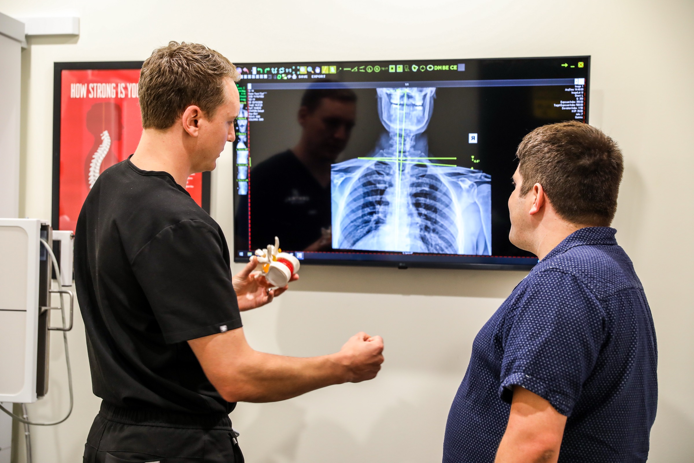 Dr. Emmerich reviewing a spine X-ray on the screen with a patient