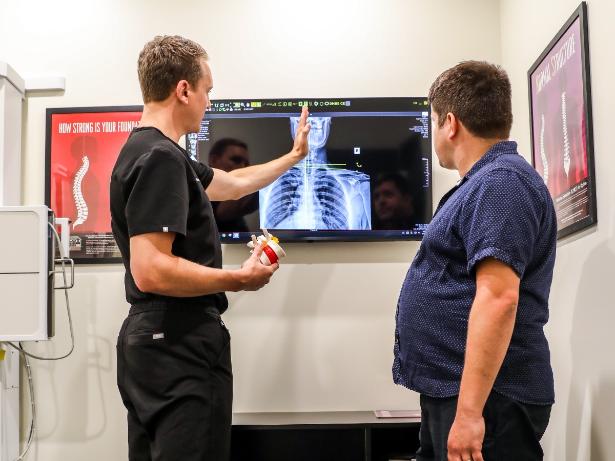 Dr. Emmerich pointing at a spine X-ray with a patient